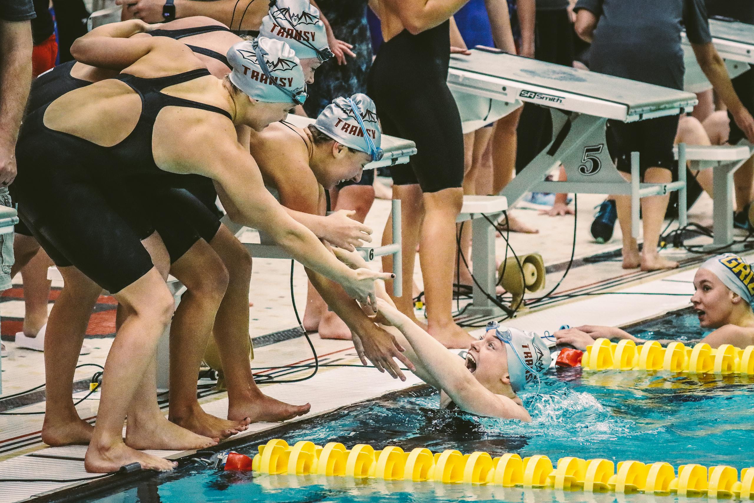 Euphoric swimmers celebrate victory at a swimming meet, showing team spirit and joy.