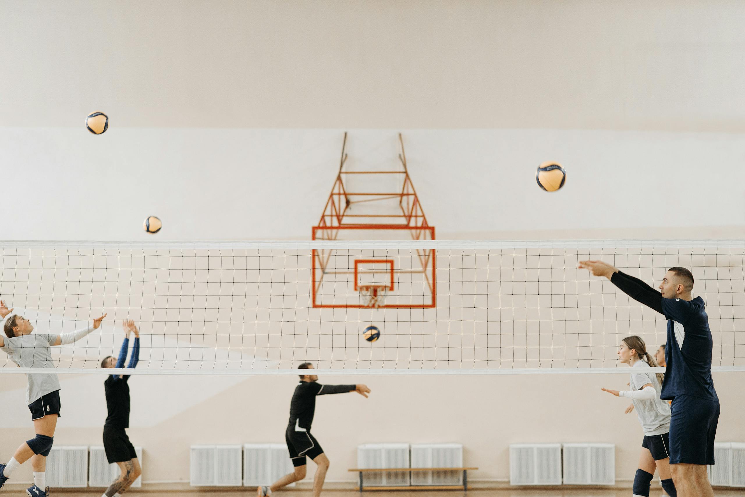 A group of young adults practicing volleyball indoors, showcasing teamwork and skill.