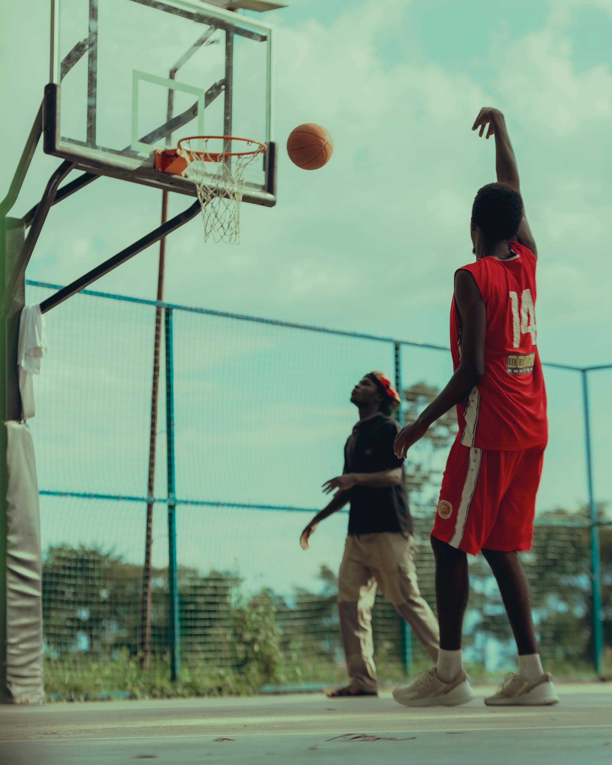 A vibrant moment on an outdoor basketball court with a player shooting a basket.
