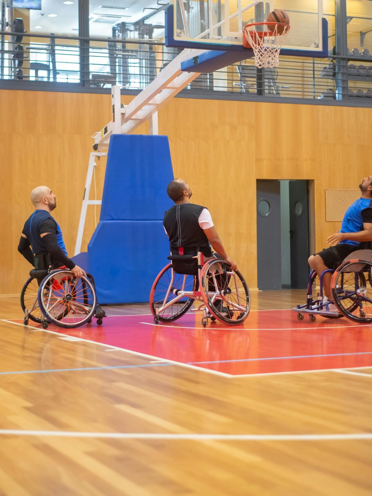 Athletes playing wheelchair basketball in a sports hall, showcasing teamwork and skill.