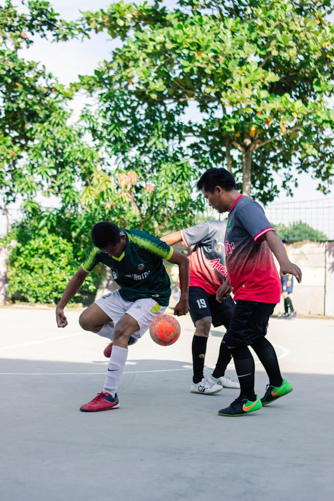 Three young men playing soccer outdoors on a sunny day, displaying skill and teamwork.